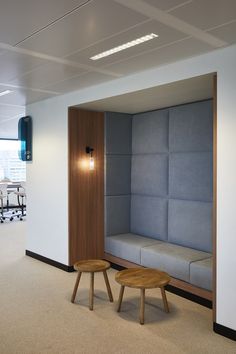 two wooden tables sitting next to each other in an office space with white walls and blue upholstered couches