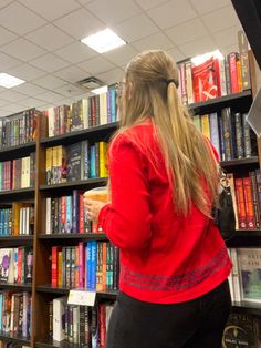 a woman standing in front of a book shelf filled with books