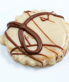 a cookie with white frosting and chocolate drizzled on top, sitting on a white surface