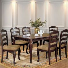 a dining room table with chairs and a vase filled with flowers on top of it