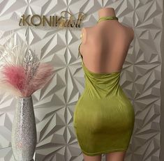 a mannequin wearing a green dress next to a vase with feathers on it