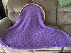 a purple blanket sitting on top of a couch