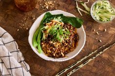 a bowl filled with food next to chopsticks on top of a wooden table