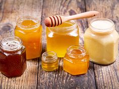 several jars filled with honey sitting on top of a wooden table