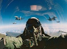 an air force pilot is looking out the window at fighter jets in the sky behind him