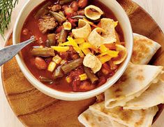 a bowl of chili and tortilla soup with pita bread on the side