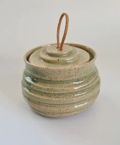 a ceramic container with a wooden handle on a white background