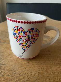 a coffee cup with a heart shaped balloon painted on the side and dots all over it