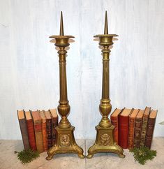 two golden candlesticks are next to some books