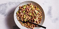 a bowl filled with beans and celery next to a spoon