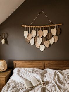 a bed with white sheets and pillows next to a wall hanging with hearts on it