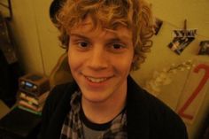 a young man with curly hair smiling at the camera