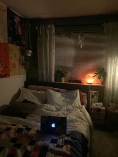 a laptop computer sitting on top of a bed next to a night stand and window