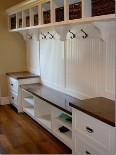 a room with some white cabinets and wooden shelves on it's sides, along with two benches