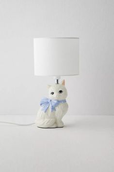 a white cat lamp with a blue bow around its neck