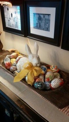 an easter basket with painted eggs in front of two framed pictures