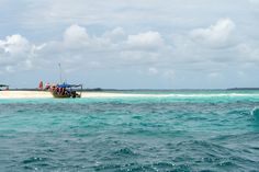 a small boat in the middle of an ocean with people standing on top of it