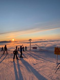 many people are skiing on the snow at sunset