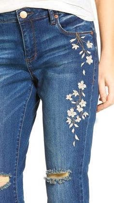 a woman wearing ripped jeans with flowers on the side