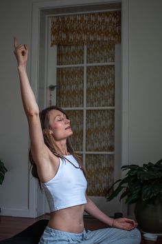 a woman is sitting on the floor doing yoga with her arms up in the air