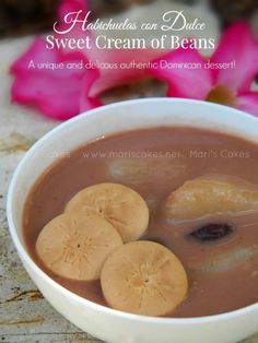 a white bowl filled with chocolate and sliced bananas on top of a table next to pink flowers