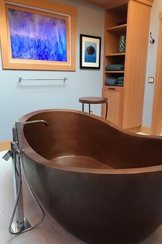 a large bath tub sitting on top of a white floor next to a wooden shelf