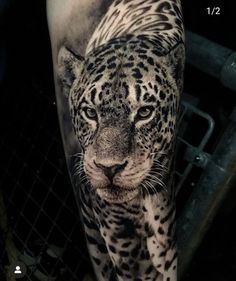 a black and white photo of a leopard on the arm with an inked design