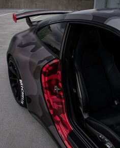 the rear end of a sports car with its door open and camouflage print on it