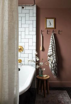 a white bath tub sitting next to a wooden table with flowers on top of it