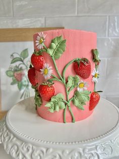 a pink cake with strawberries and daisies on it