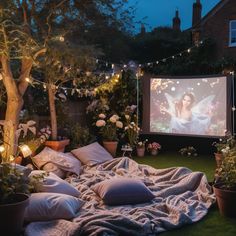 an outdoor movie is set up in the backyard with lights strung from trees and potted plants