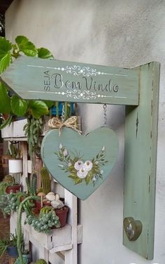 a wooden sign hanging from the side of a building next to potted plants and succulents