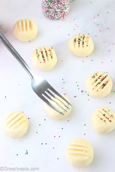 a fork is being used to cut out the frosted cookies with sprinkles