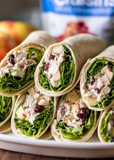 several wraps are stacked on a plate with apples and cranberries in the background