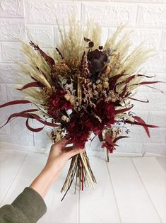 a hand holding a bouquet of dried flowers