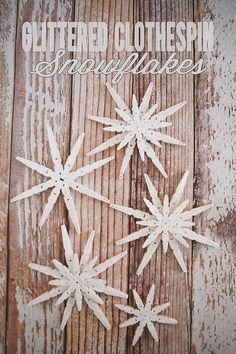 three snowflakes are sitting on top of a wooden surface with the words glittered clothespin