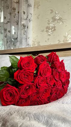 a bouquet of red roses sitting on top of a bed