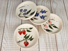 four plates with flowers and berries painted on them