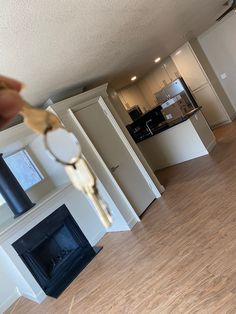 a person holding a house key in front of an open living room and kitchen area