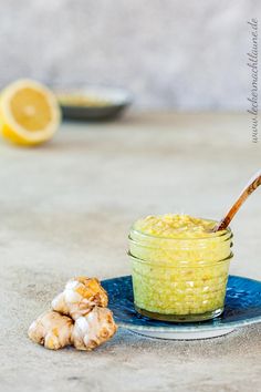 a jar filled with food sitting on top of a blue plate next to a lemon wedge