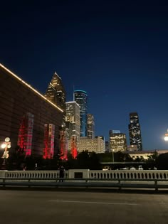 the city skyline is lit up at night with red lights and buildings in the background