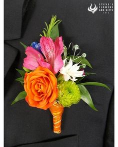 a boutonniere with flowers and greenery on the lapel of a suit