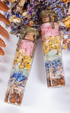 two glass bottles filled with different types of flowers and rocks sitting on top of each other