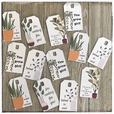 tags with plants and sayings on them sitting on a wooden table next to each other