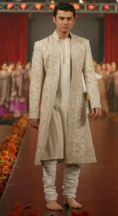 a man is walking down the runway wearing a white suit and jacket with sequins on it