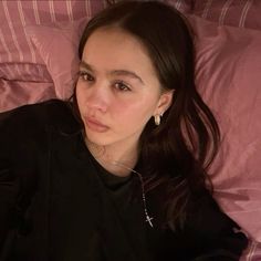 a woman laying on top of a bed next to a pink comforter covered in pillows