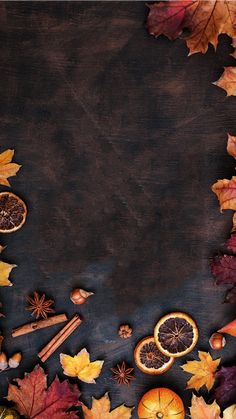 an overhead view of autumn leaves, oranges and spices on a black background with space for text