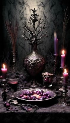 a table topped with candles and an ornate vase filled with purple balls on top of it