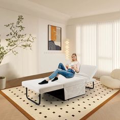 a woman sitting on top of a white couch in a living room next to a potted plant