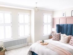 a large bed sitting next to two windows with shutters on each side in a bedroom